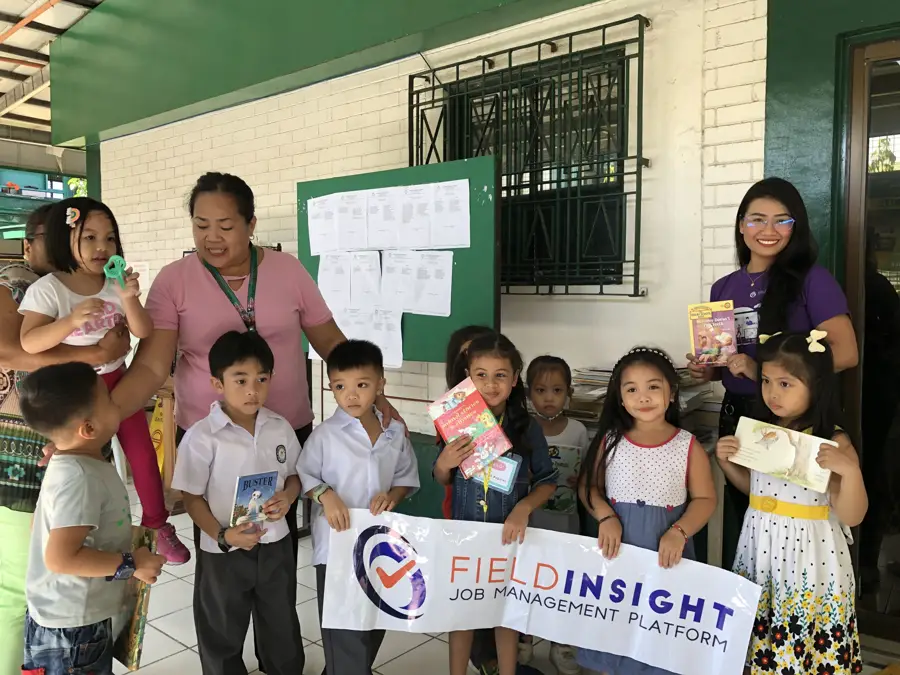 Joy with school children holding a FieldInsight banner