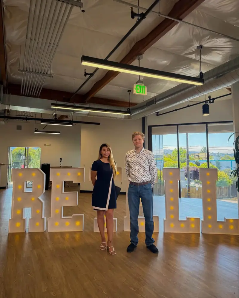 Joy with a colleague in front of the Retell sign